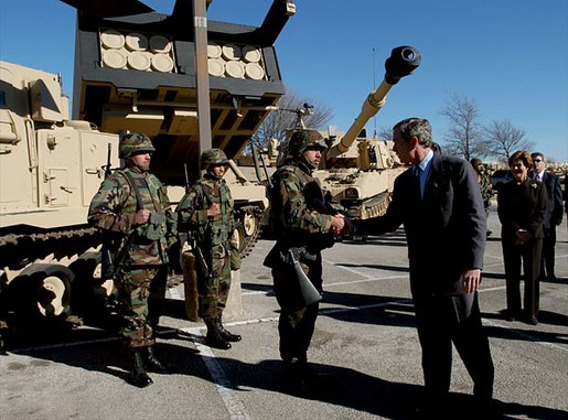 President George W. Bush shaking hands with soldiers at Fort Hood with a tank in the background,