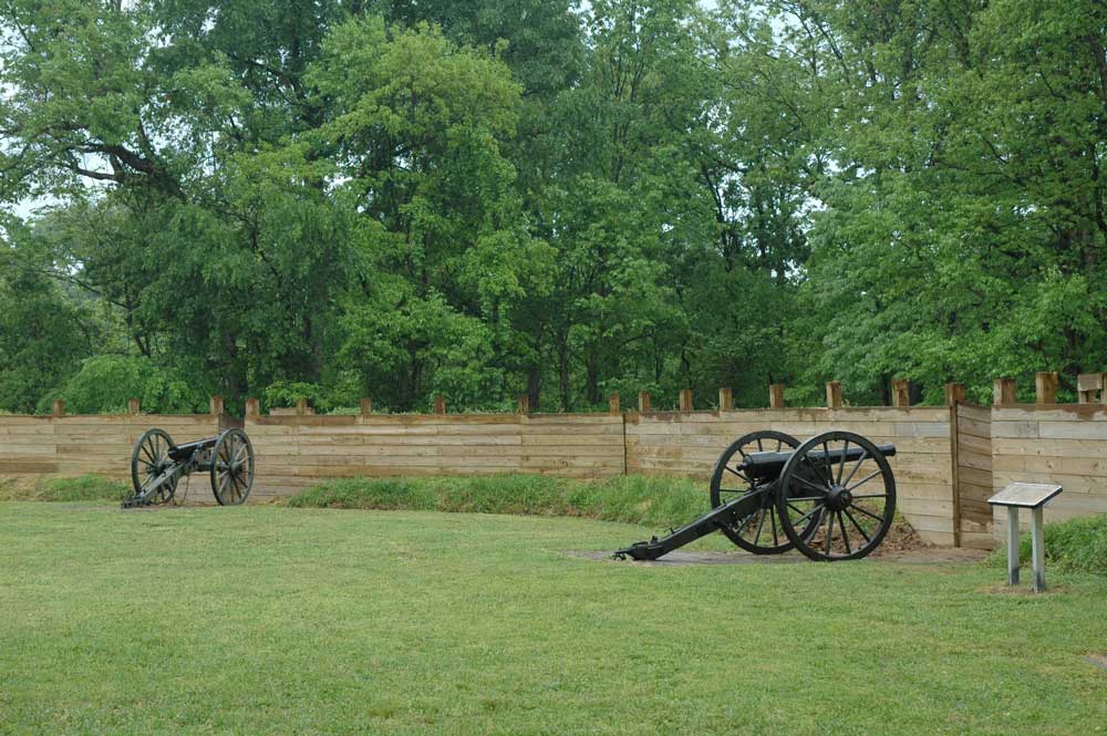 Two cannons at Fort Pillow on green lawn with trees in the background.